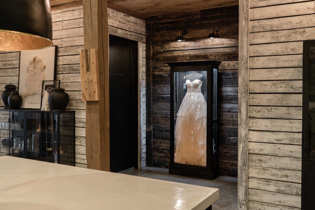 A freestanding Mrs. Case Signature displaying a gown in a whitewashed wood hallway